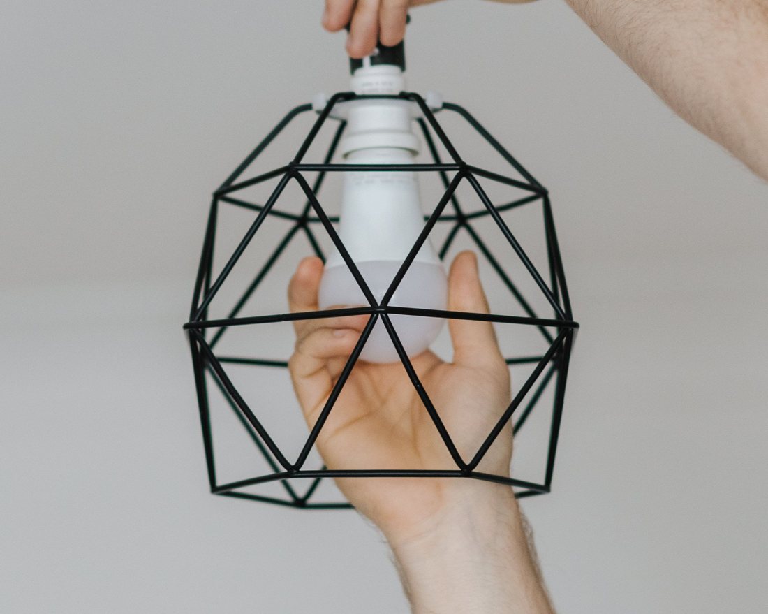 Licensed stock photograph: two hands fitting a caged pendant light to a ceiling rose.